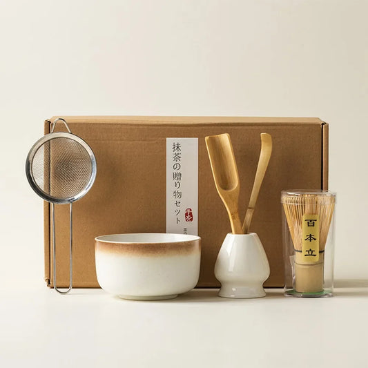 A complete matcha tea kit featuring a bamboo whisk, ceramic bowl, and tools beautifully arranged in a gift-ready box